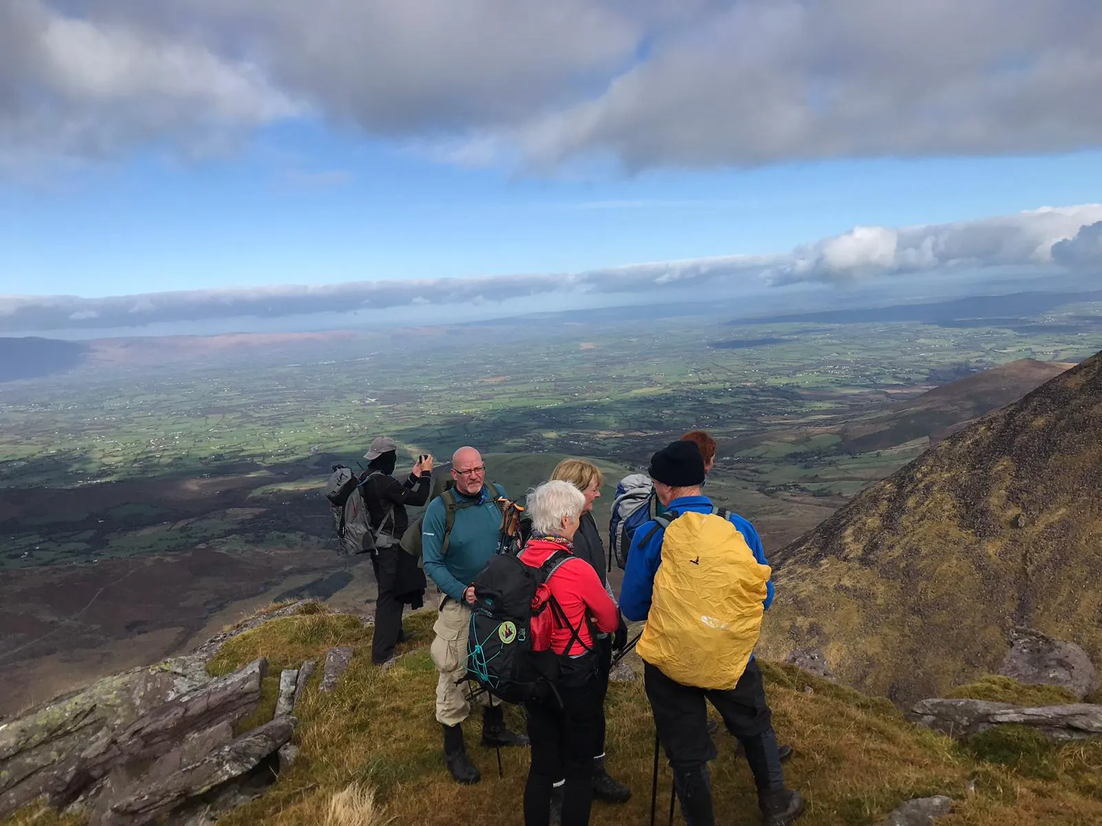 Club members looking out over a wide valley from a rocky summit