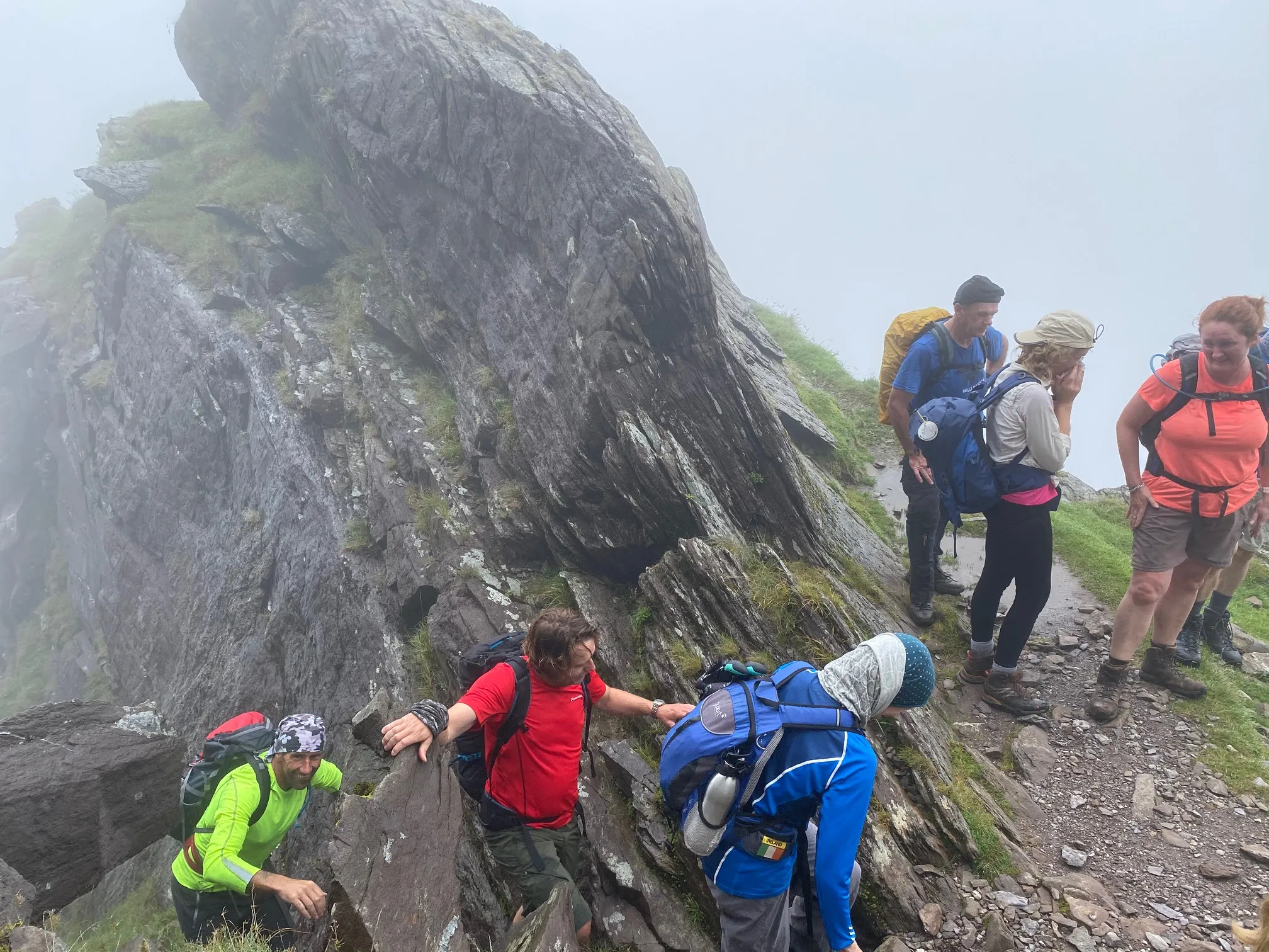 Club members scrambling up a rocky section in the mist