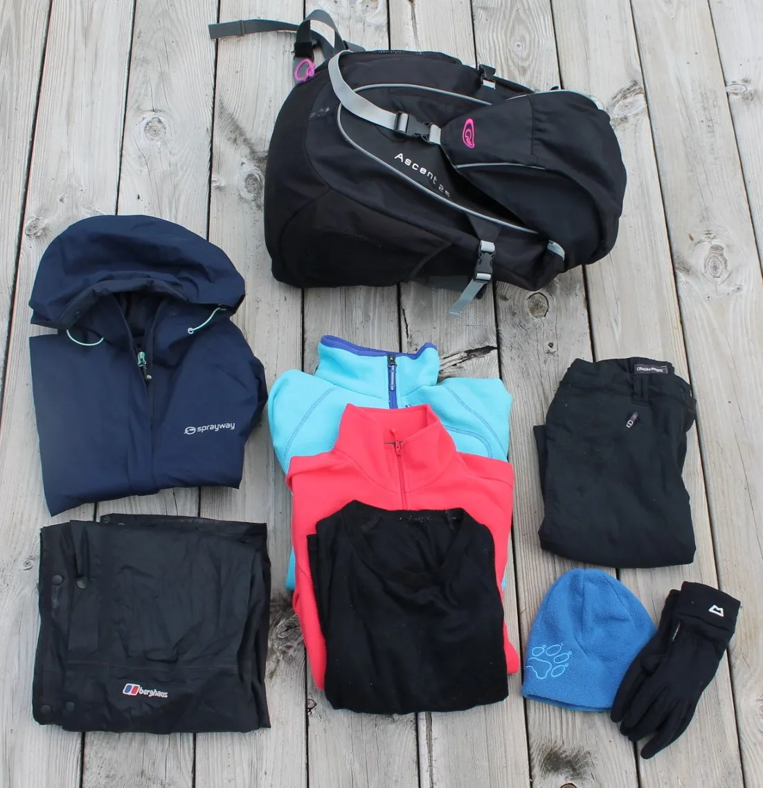Hiking clothes laid out in layers: base layer, fleece, waterproof jacket and trousers